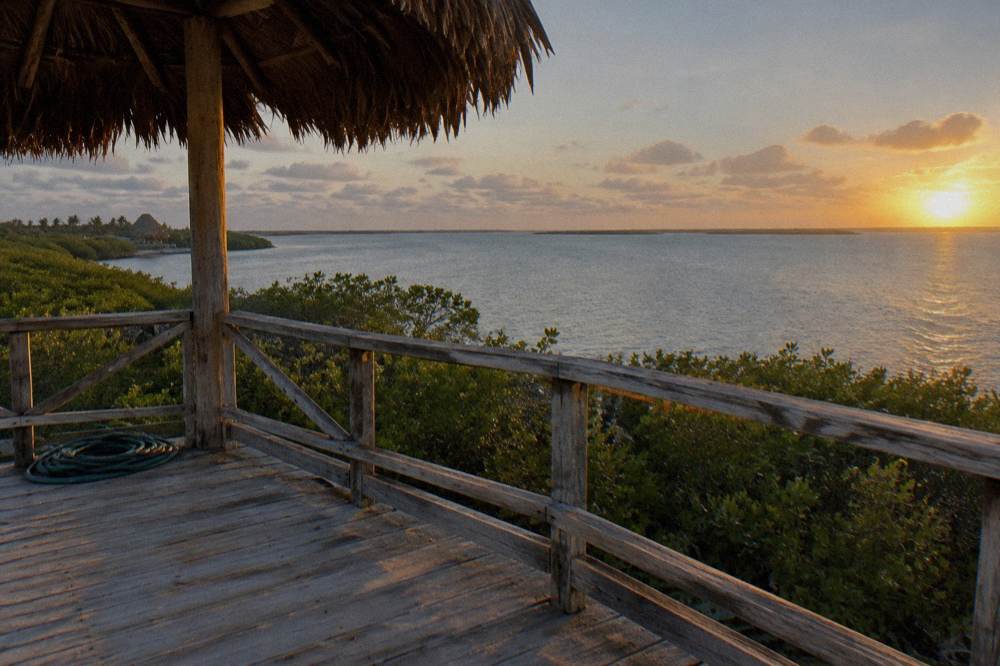 An empty wooden observation deck above a wide lagoon at golden hour