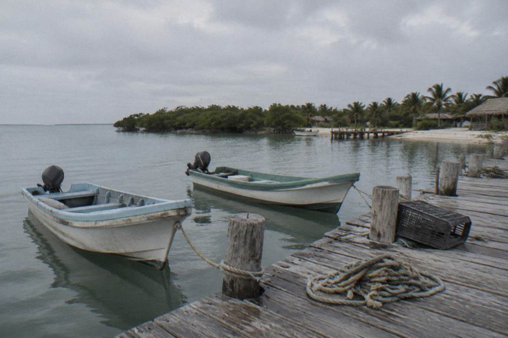 Small boats moored at a wooden dock on a wide calm lagoon at soft morning light