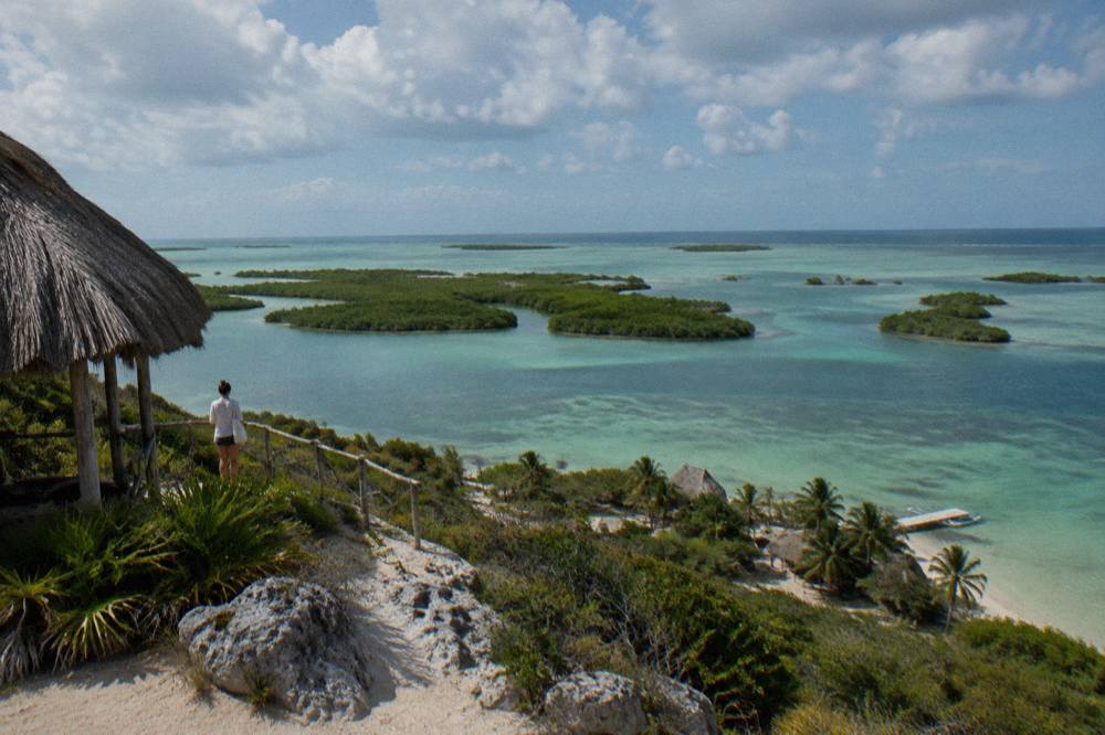 Wide lagoon dotted with mangrove islands under scattered clouds along a Caribbean coastline
