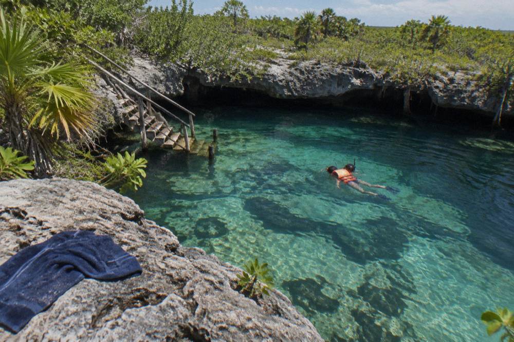 Snorkeler in a life vest floating over shallow reef water