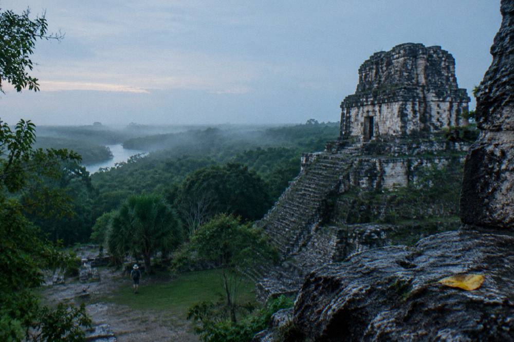 Ancient stone structure rising above dense low jungle under a wide sky