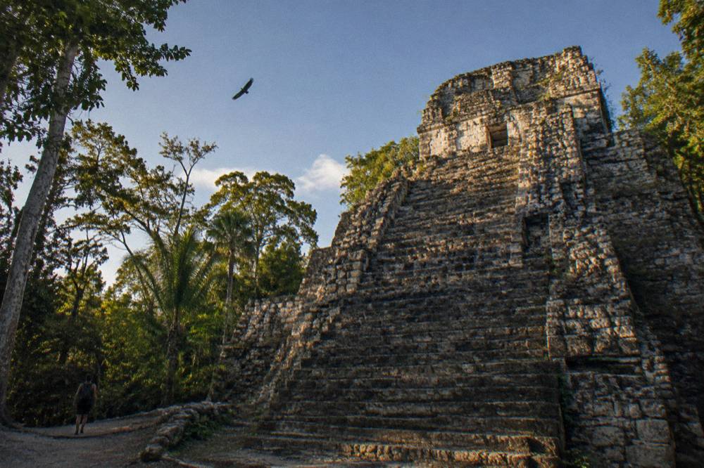 Ancient stone structure of Muyil rising above tall tropical forest