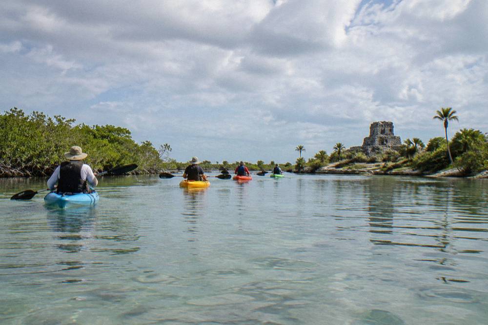 A line of kayaks crossing a wide lagoon at low angle near the water surface