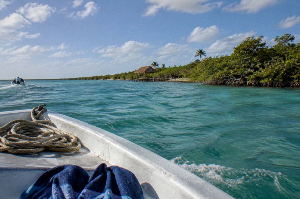 Open boat on turquoise lagoon water under scattered clouds