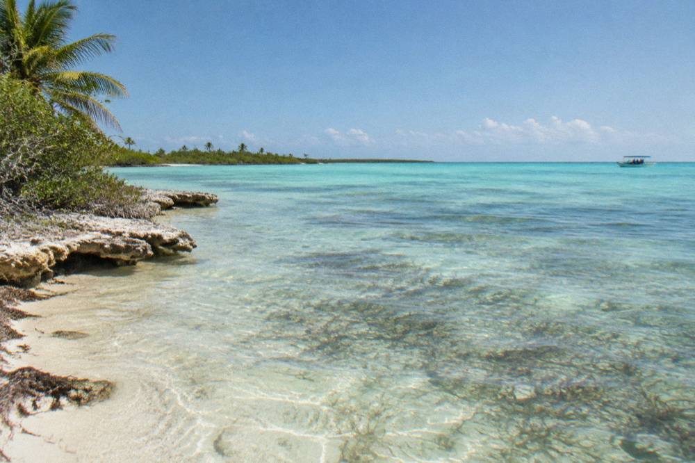 Turquoise shallow Caribbean water over sea grass beds with a distant boat